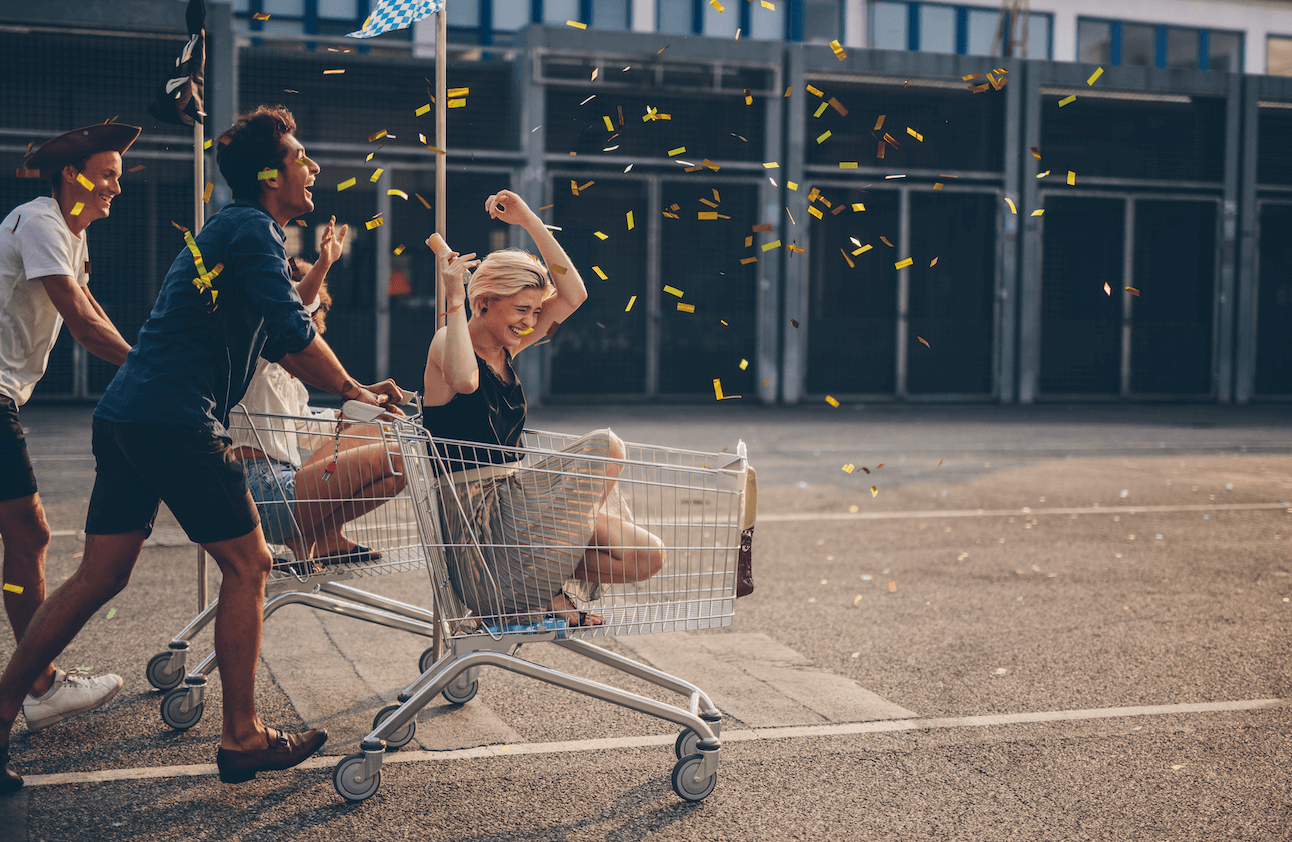 Friends pushing another friend in a shopping trolley